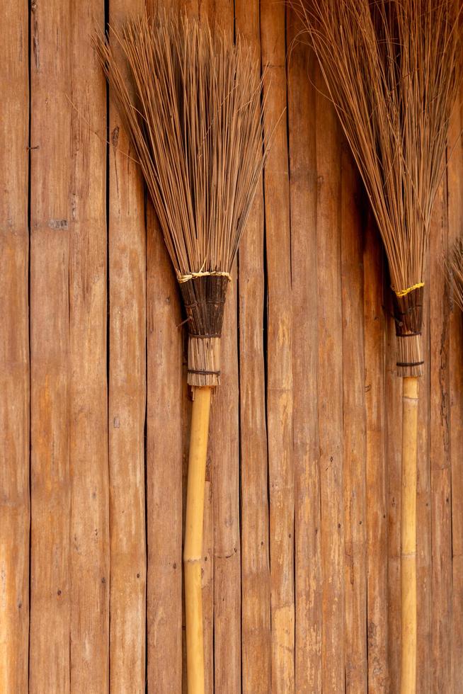 The broom is leaning against a wooden wall. photo