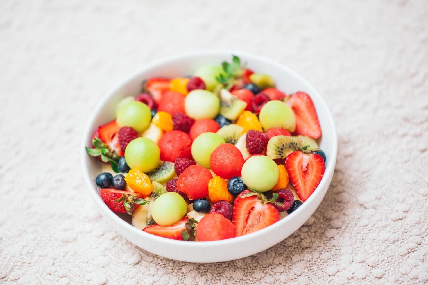 ensalada de primavera de frutas saludables. concepto de dieta saludable. deliciosas bayas frescas en un tazón. enfoque selectivo. vista superior. frutas coloridas mezcladas en ensalada casera. concepto de nutrición foto