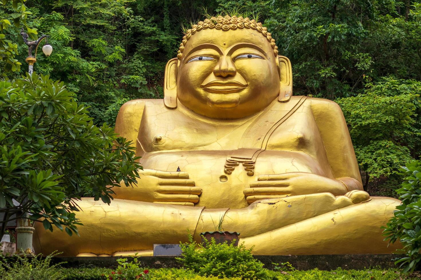 Large golden statue of Sangkhachai Buddha amid forest. photo