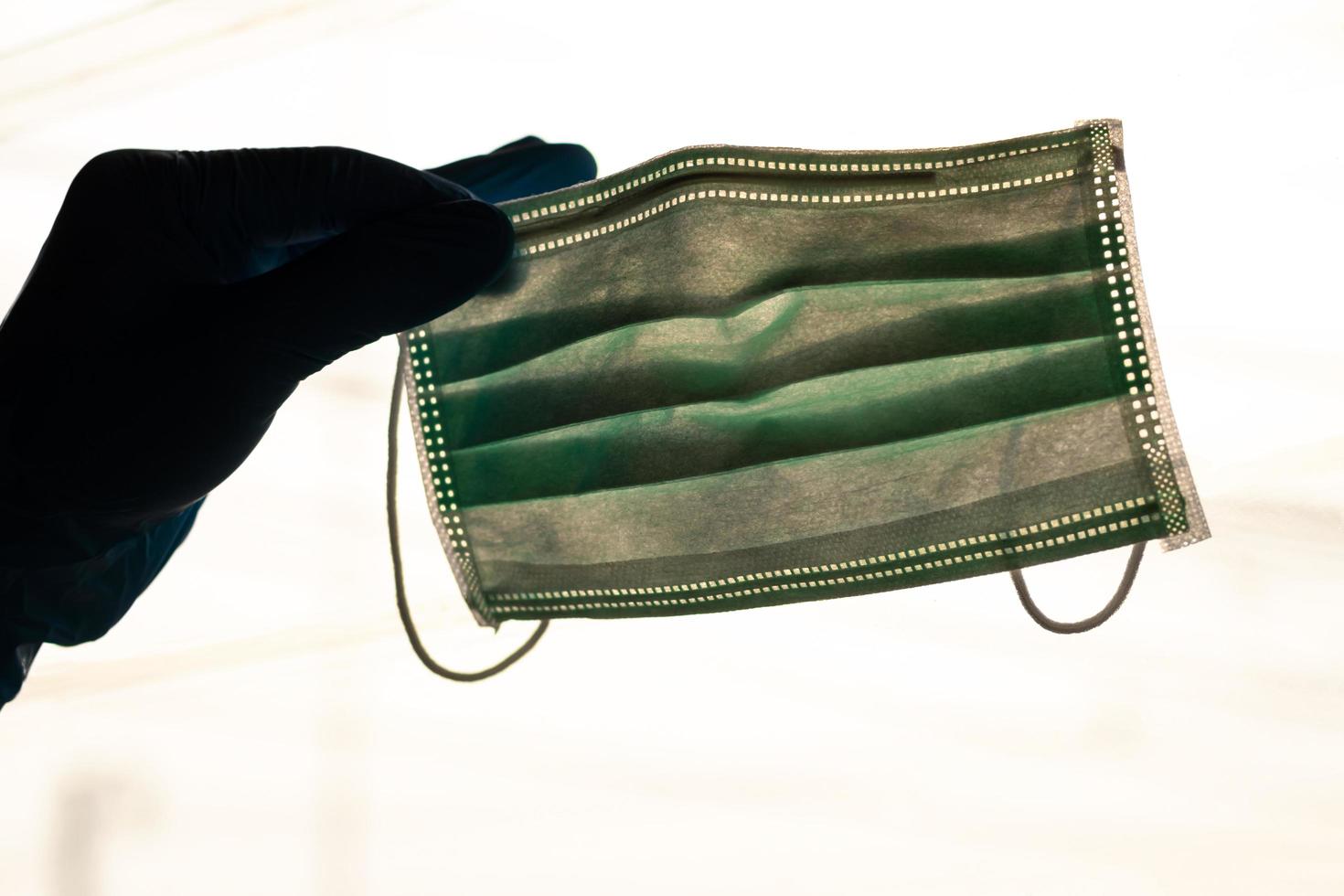 Backlit hand gloves holding a mask. photo