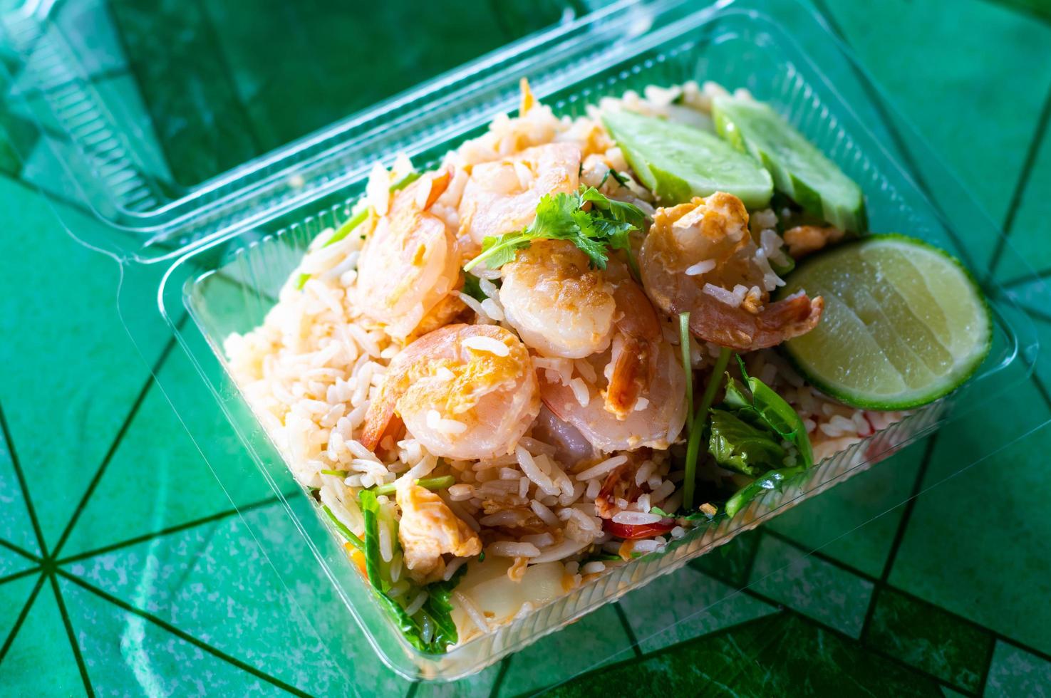 arroz frito cubierto con camarones en una caja de plástico. foto
