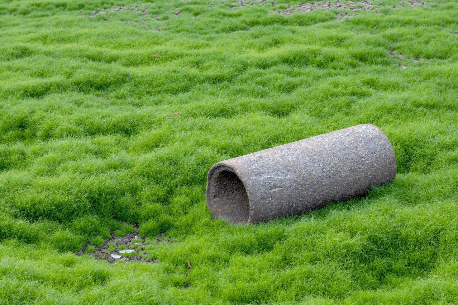 una vieja tubería de hormigón en un suelo agrietado con hierba. foto