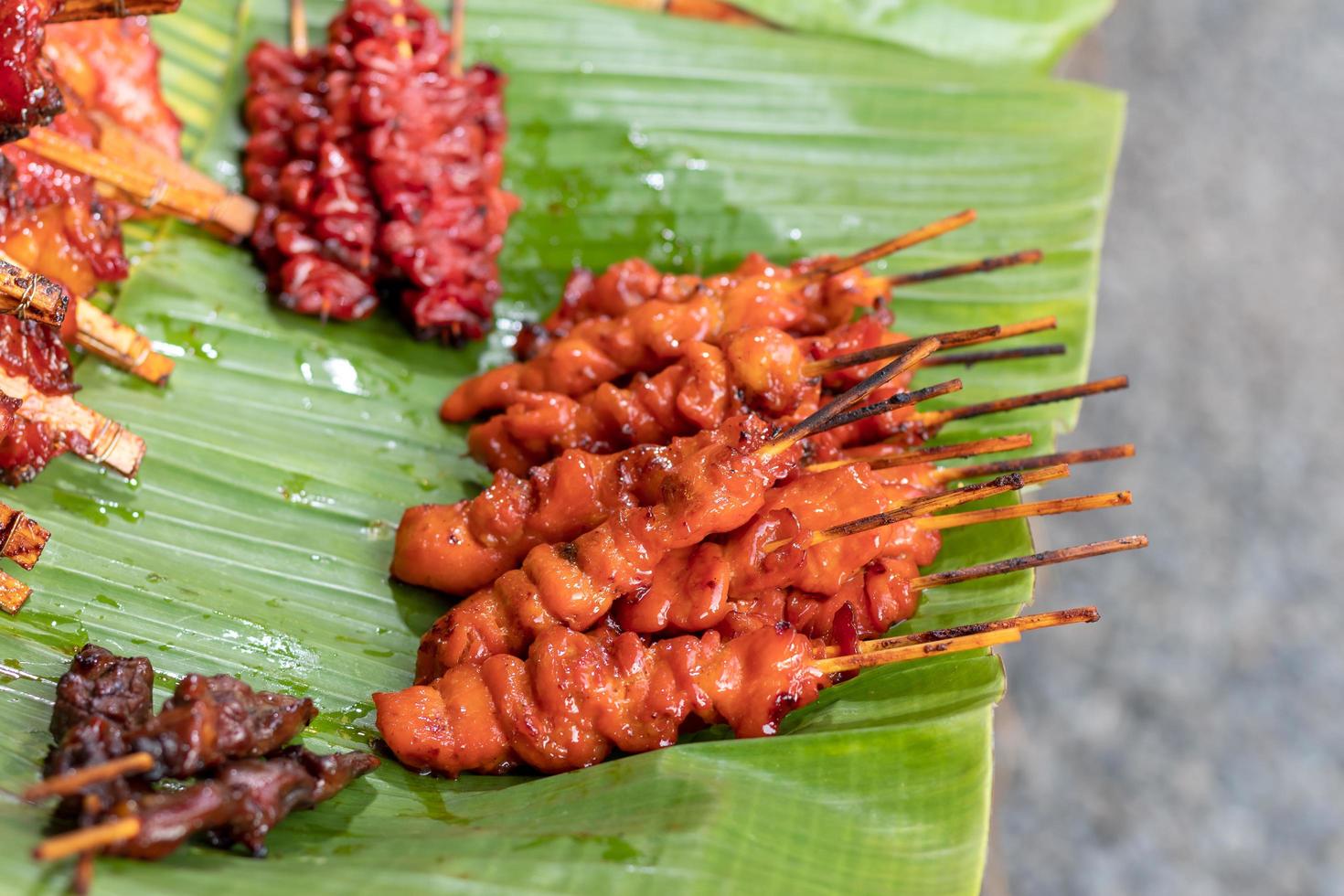 Grilled chicken on skewers placed on a banana leaf. photo
