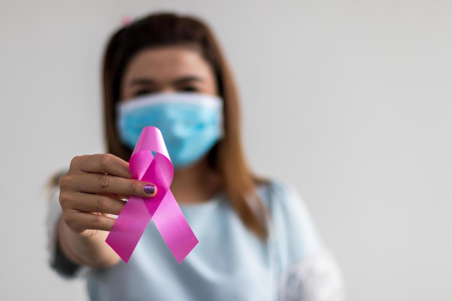 mujer de mano cercana usa una máscara como símbolo contra el cáncer de mama. foto