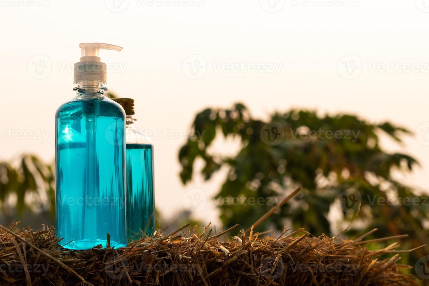 Blue gel bottles and alcohol placed on a straw in the countryside. photo