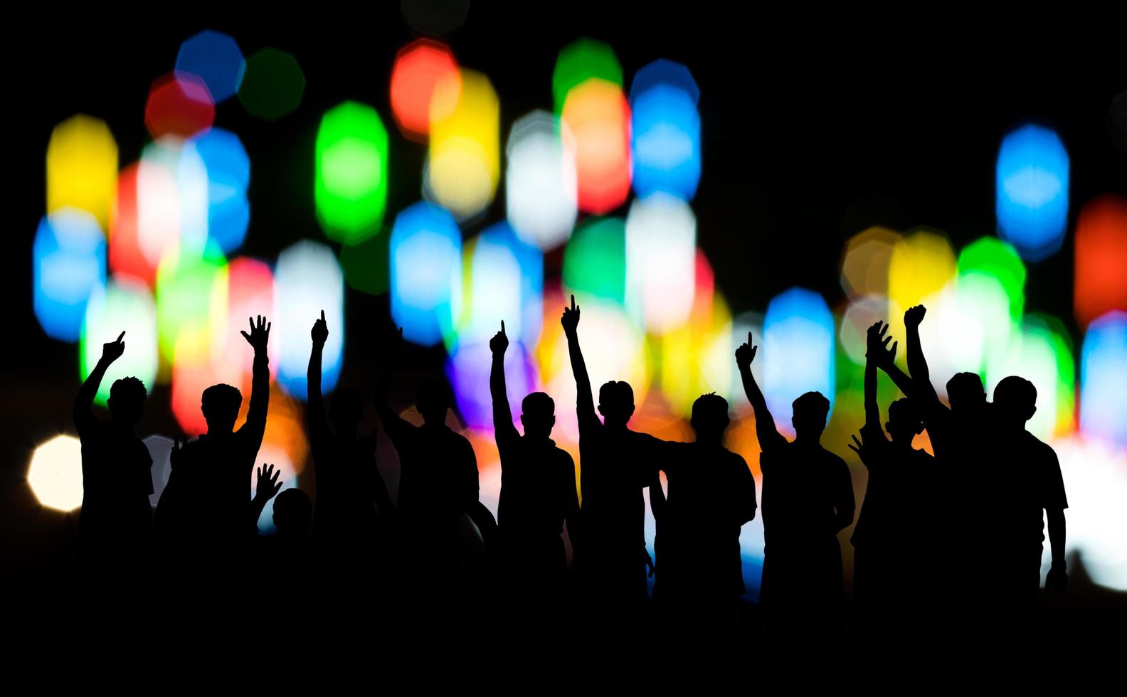 silueta, un grupo de personas levantó la mano con bokeh. foto