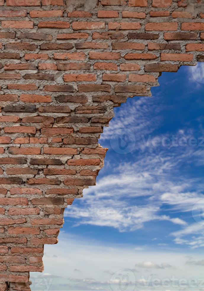 viejo muro de ladrillo rompiendo con nubes de cielo. foto