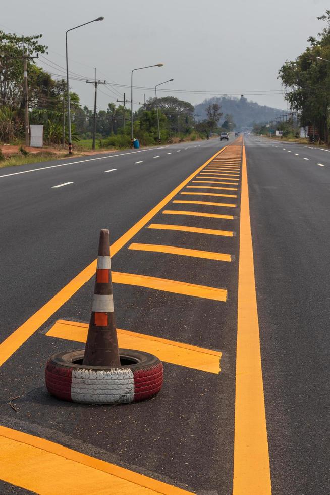 Rubber cone and yellow line strip on the road. photo