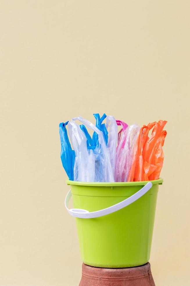 Plastic bags are packed in a green container with a yellow concrete wall. photo