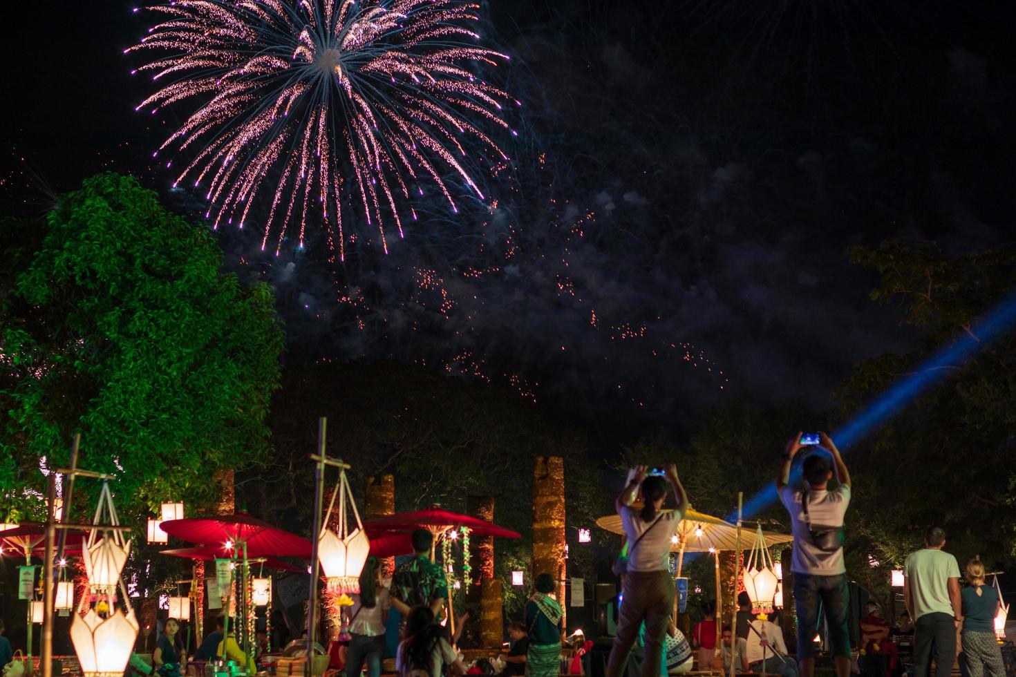 Fireworks over the trees and people at the festival. photo