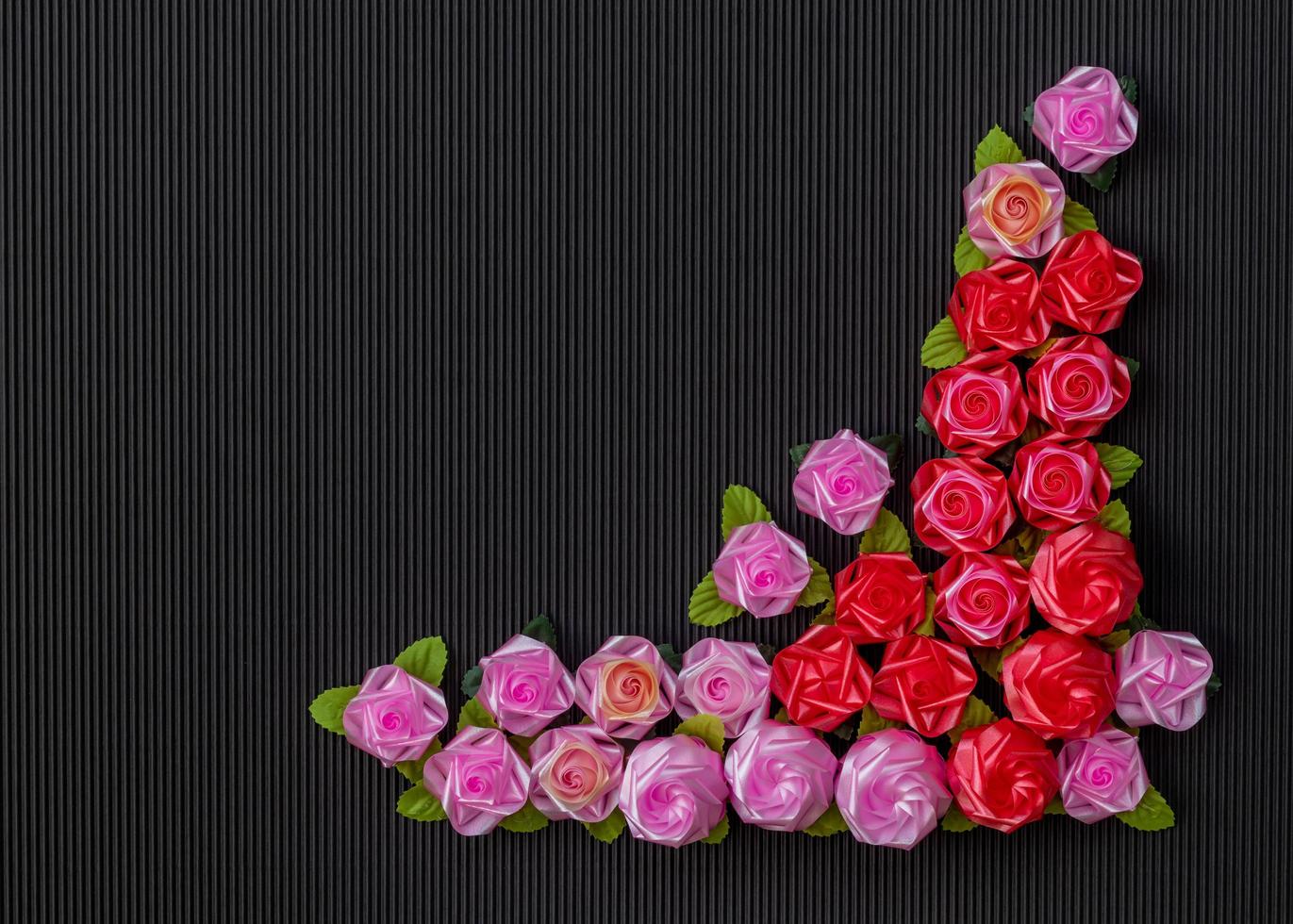 Artificial pink roses on a red background, black, corrugated. photo