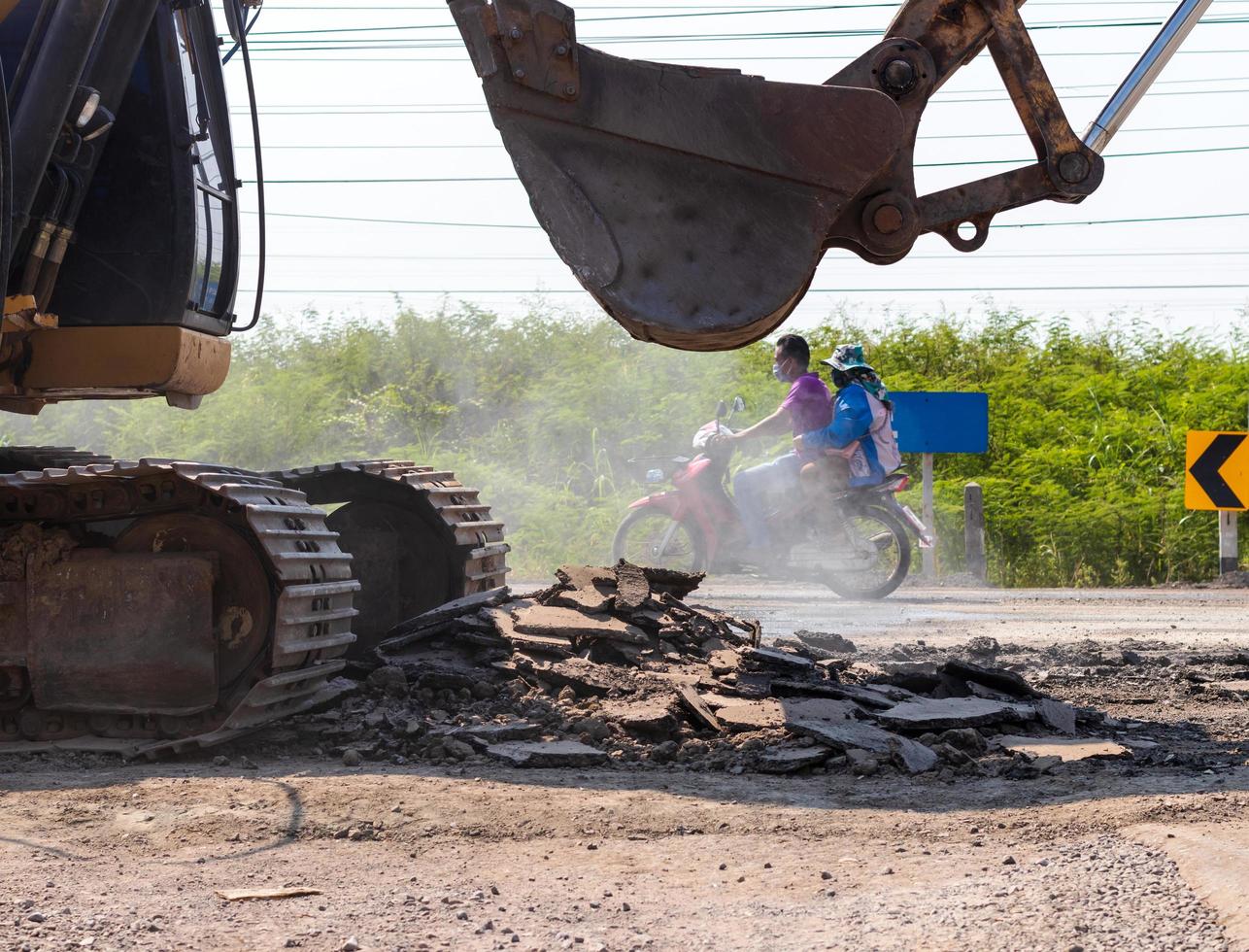 Backhoe shovel demolishing asphalt road. photo