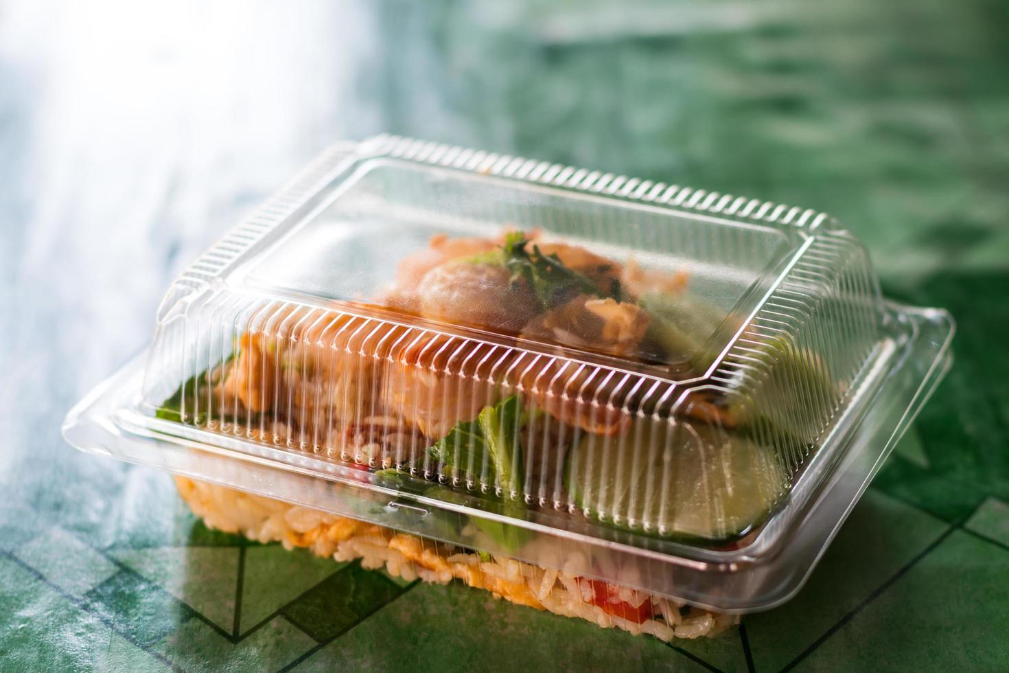 Fried rice topped with shrimp in a plastic box. photo