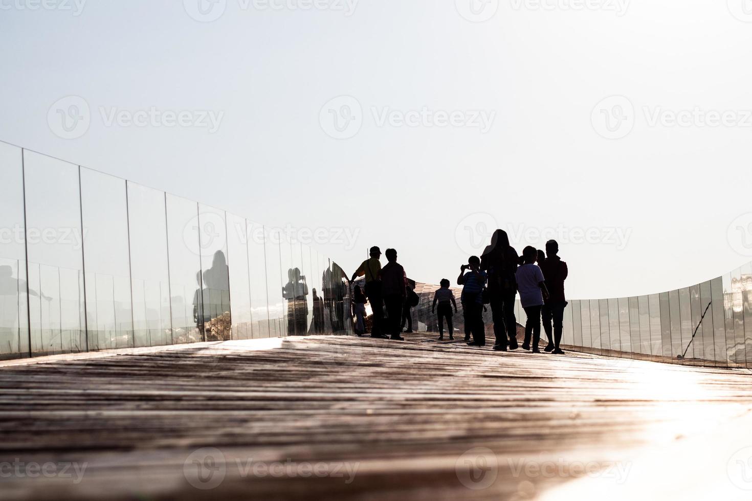 Silhouette people on the old wooden boat bridge. photo