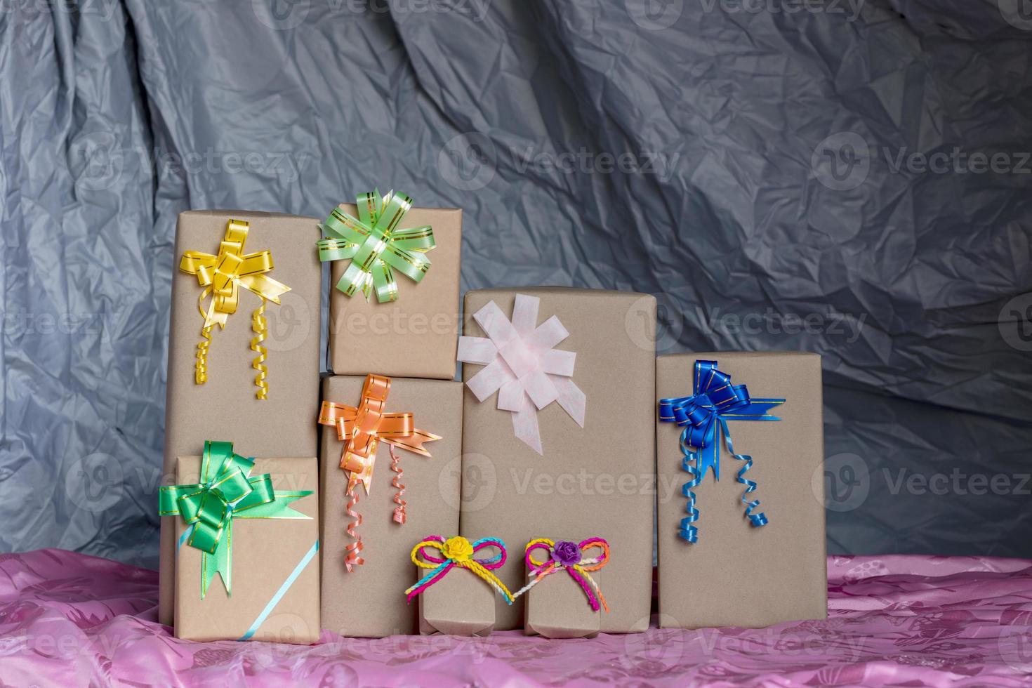 Numerous gift boxes tied with a bow inside a gray canvas. photo