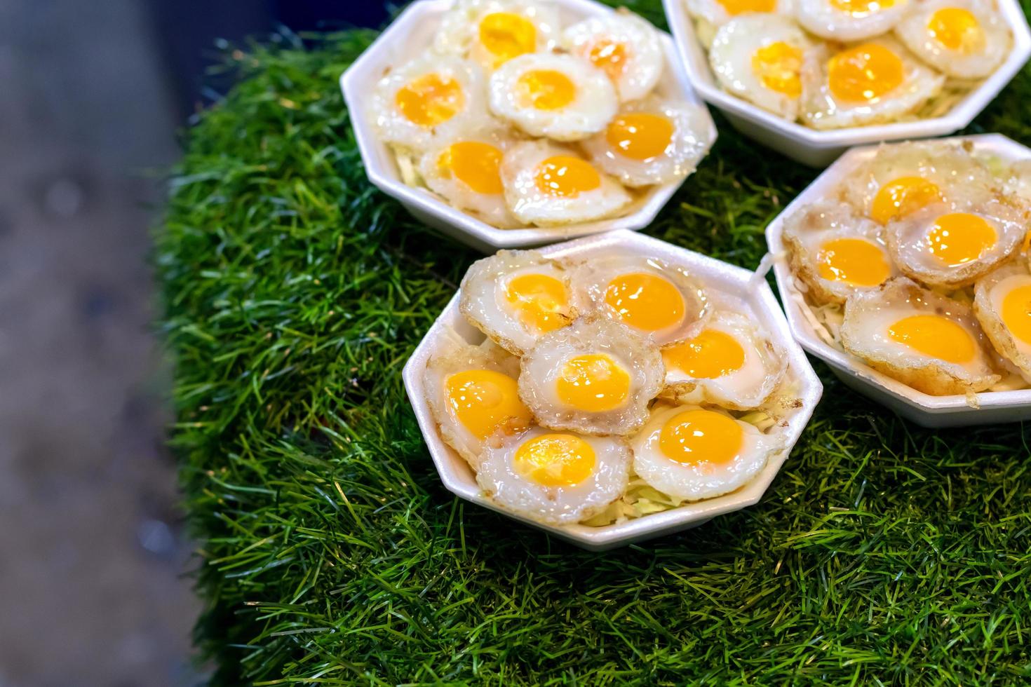 Fried quail eggs in foam boxes on artificial grass. photo