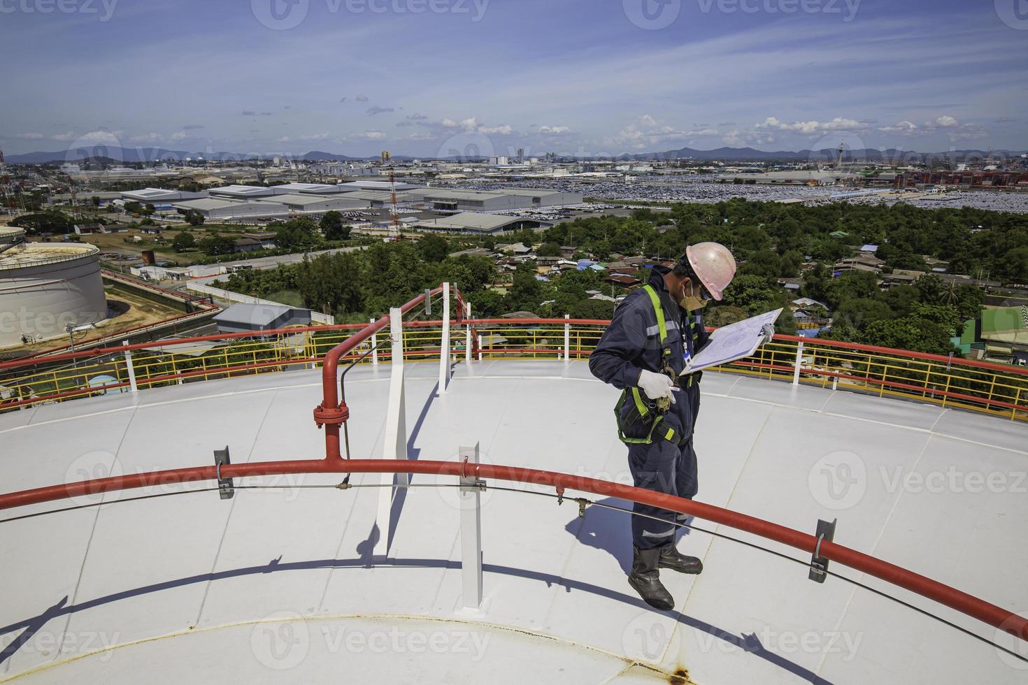 Male worker inspection visual roof storage tank oil background city. photo