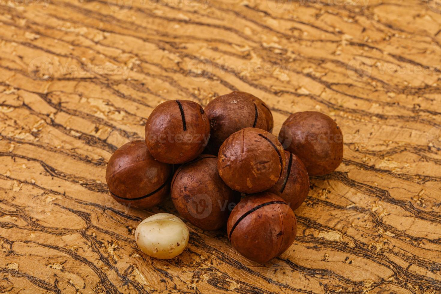 Brown macadamia nut heap over background photo
