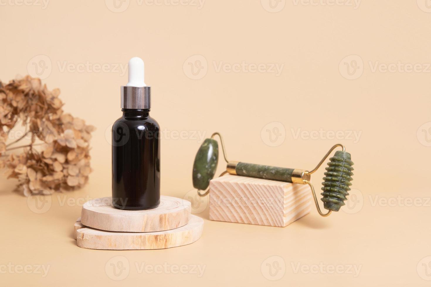 Dropper bottle with cosmetic oil and face massager on wooden podiums. Face care concept in rustic style photo