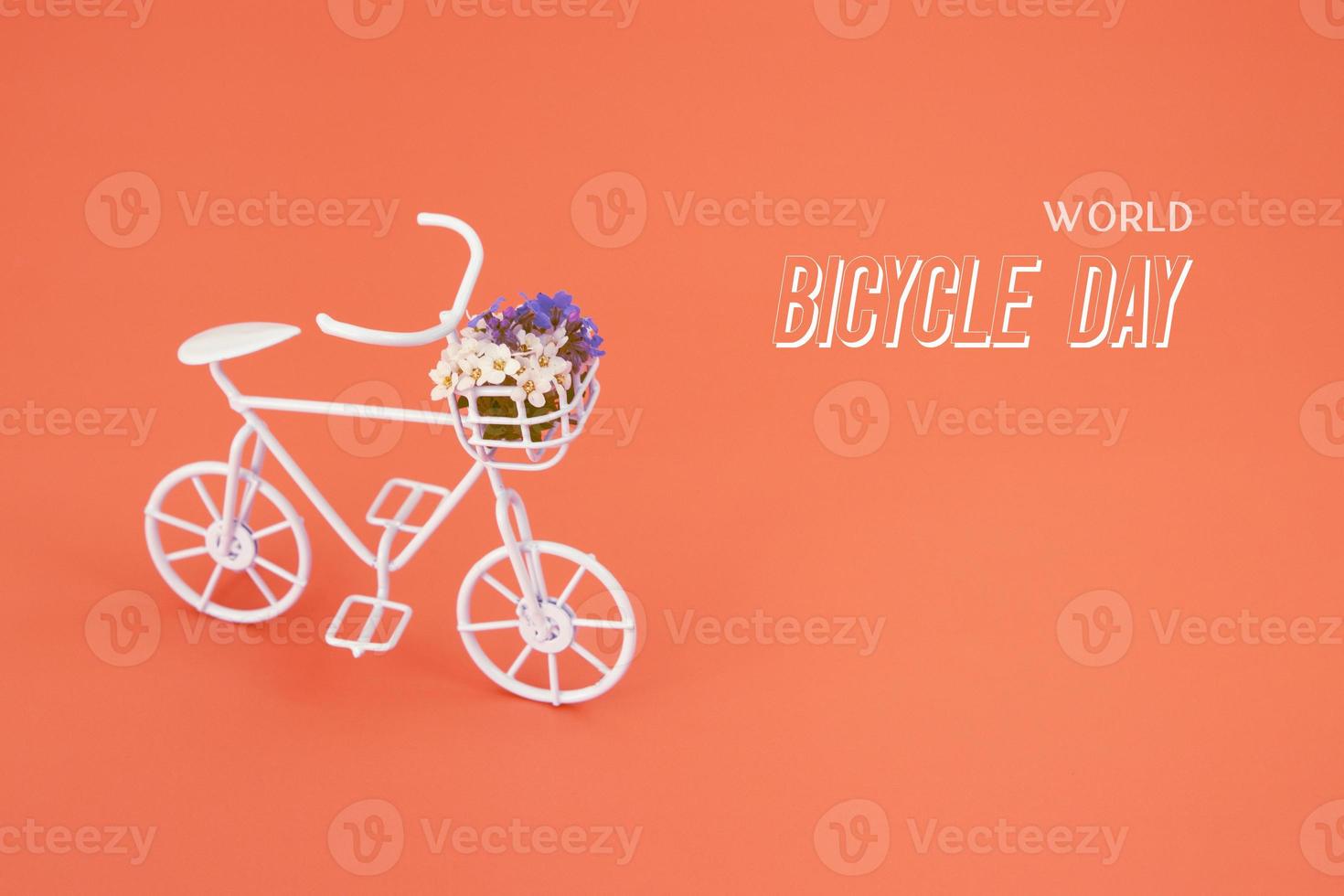 Decorative bicycle with flowers and text World Bicycle day on orange background photo