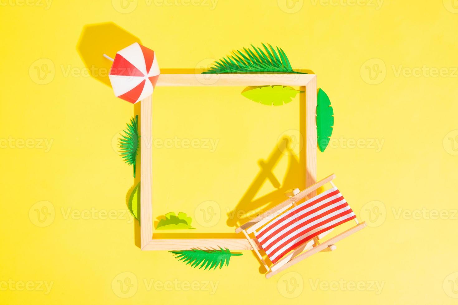 Wooden frame with beach chair and umbrella and tropical leaves with copy space top view photo