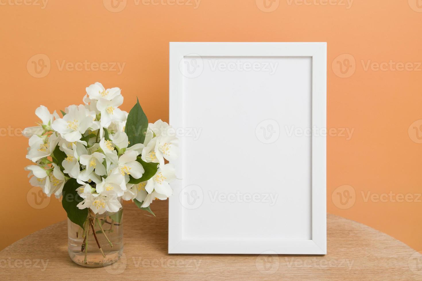 Mock up empty white frame on a round table with jasmine flowers on orange background. Place your text or image photo