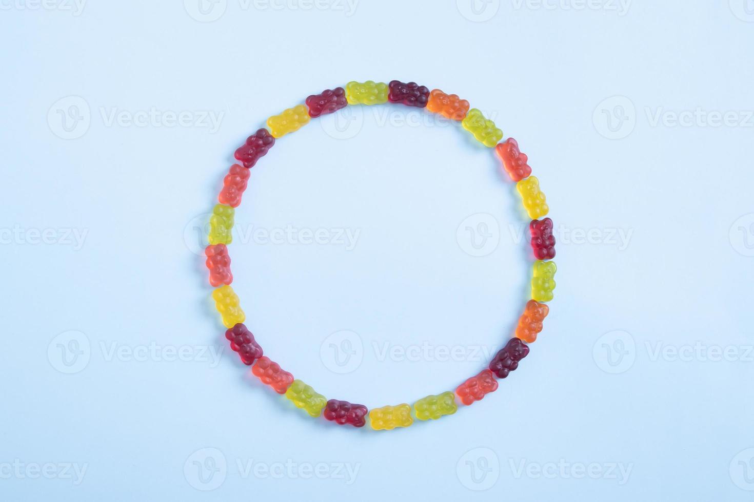 Circle of colored jelly bears on a pastel blue background. Top view photo