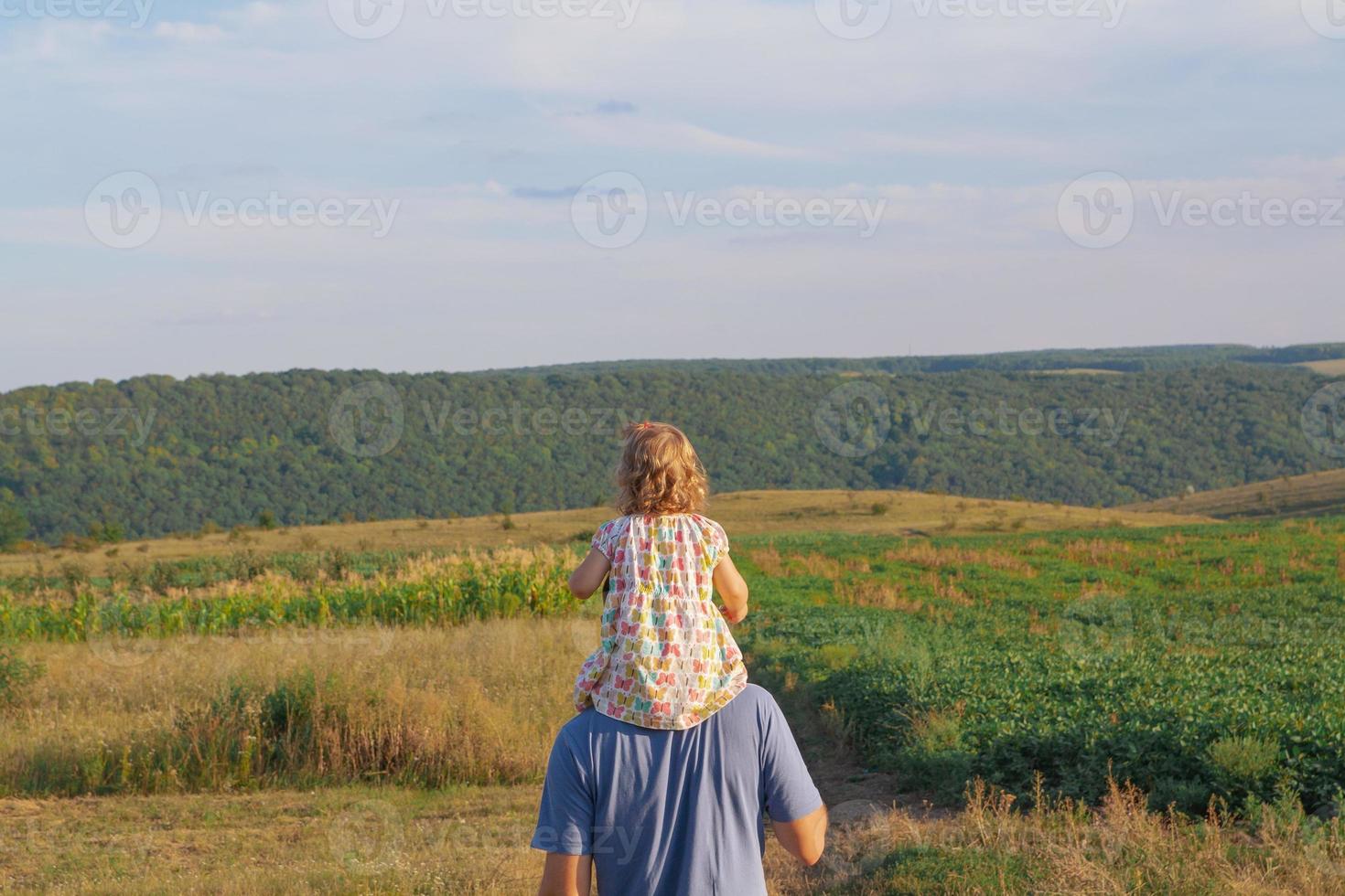 padre con hijo a hombros en el jardín. familia en la naturaleza en el concepto de pueblo foto