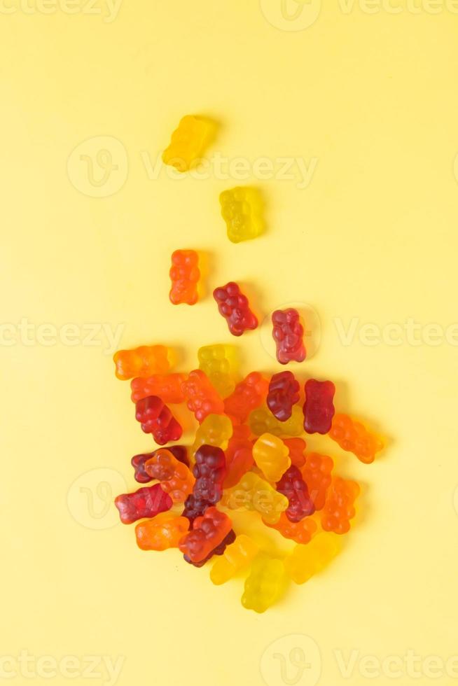 Colored jelly bears on an yellow background. Top view photo