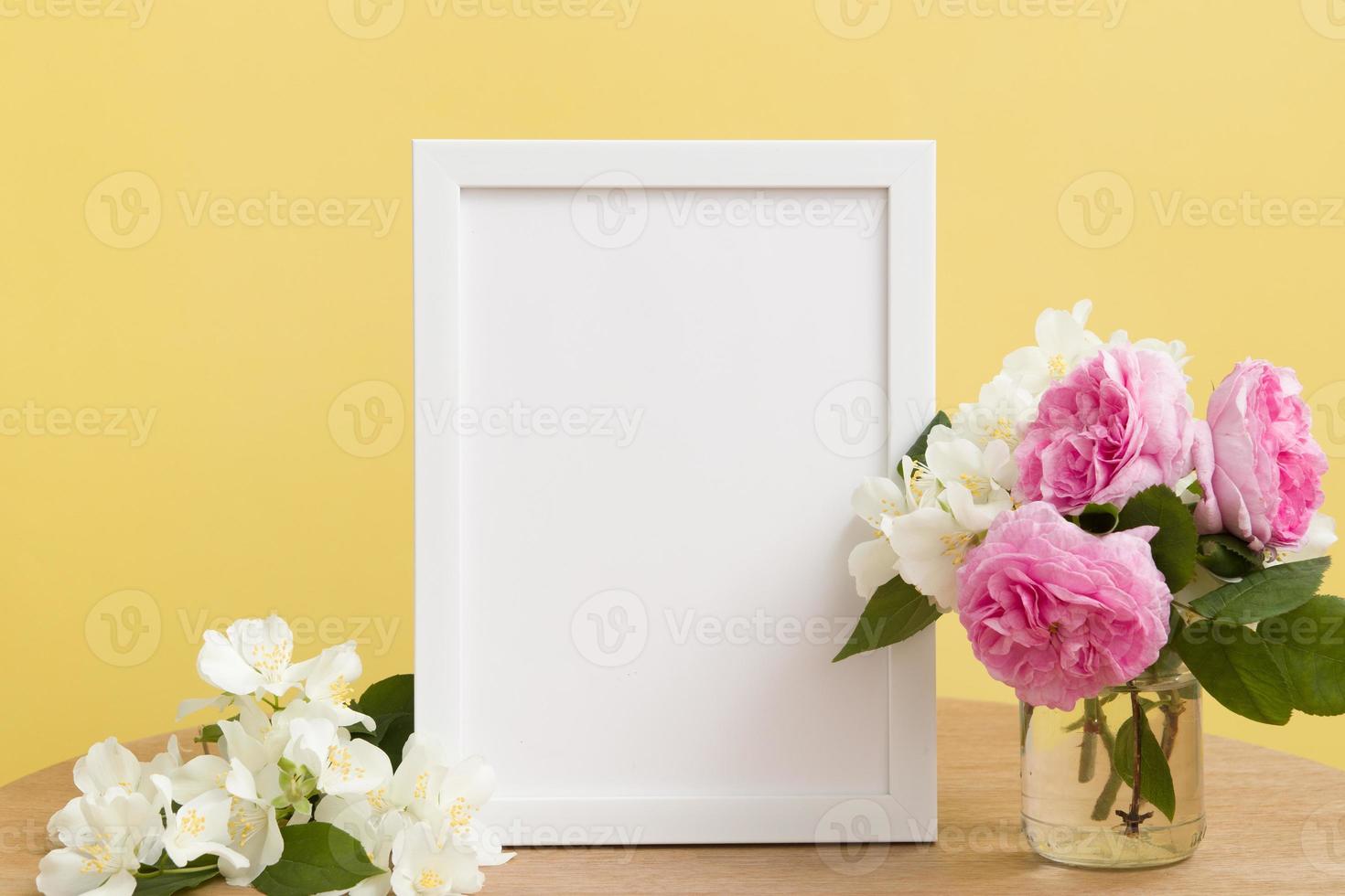 Empty white frame mock up with flowers on yellow background. Temlate for your text or picture photo
