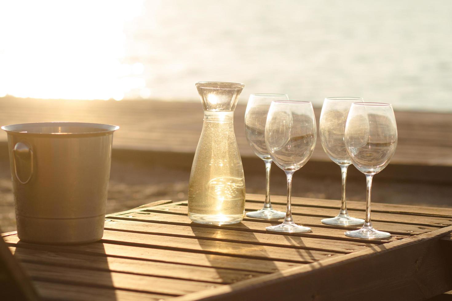 bottle of wine, glasses and ice on wooden table, summer beach background photo