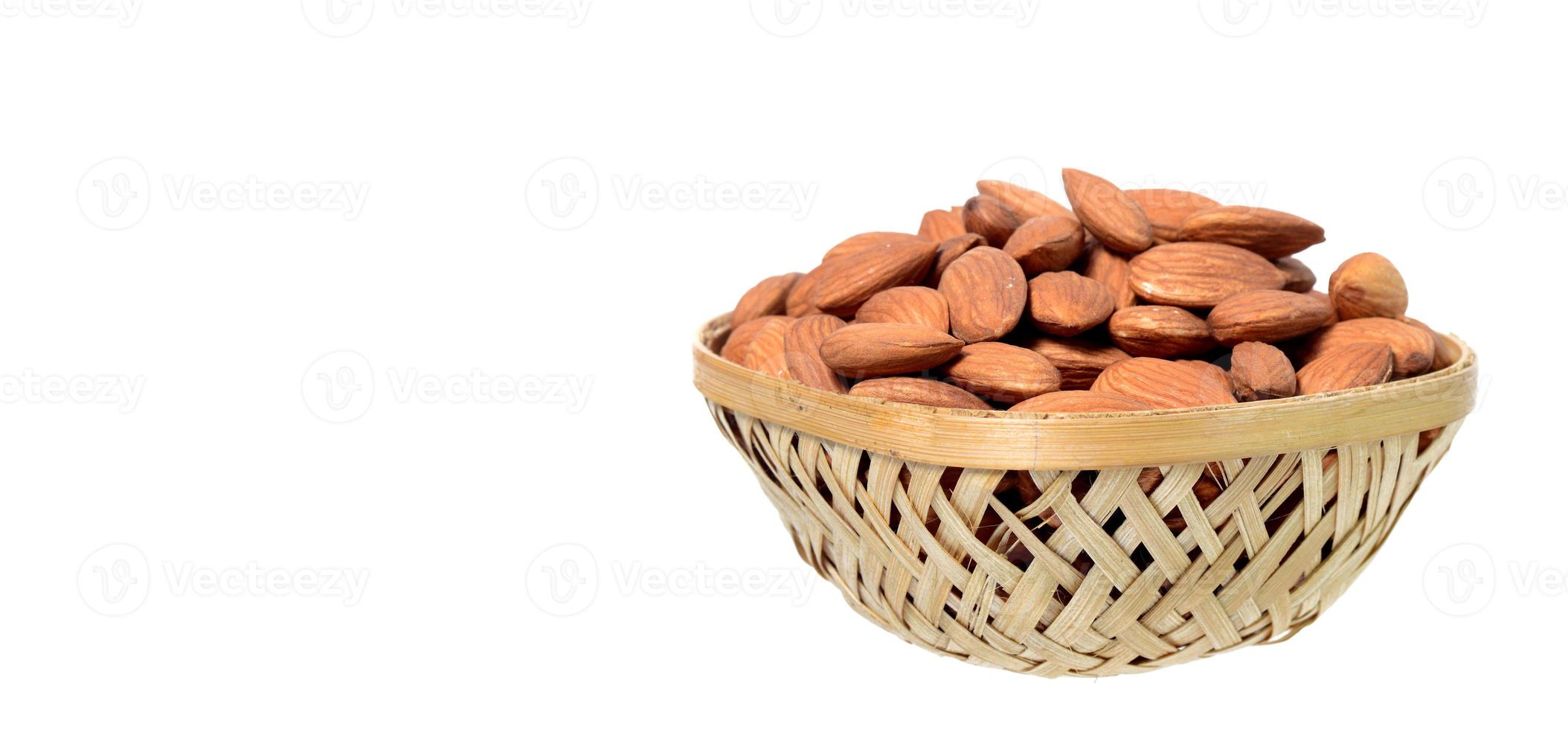 Almonds in a wooden basket with heap isolated on a white background photo
