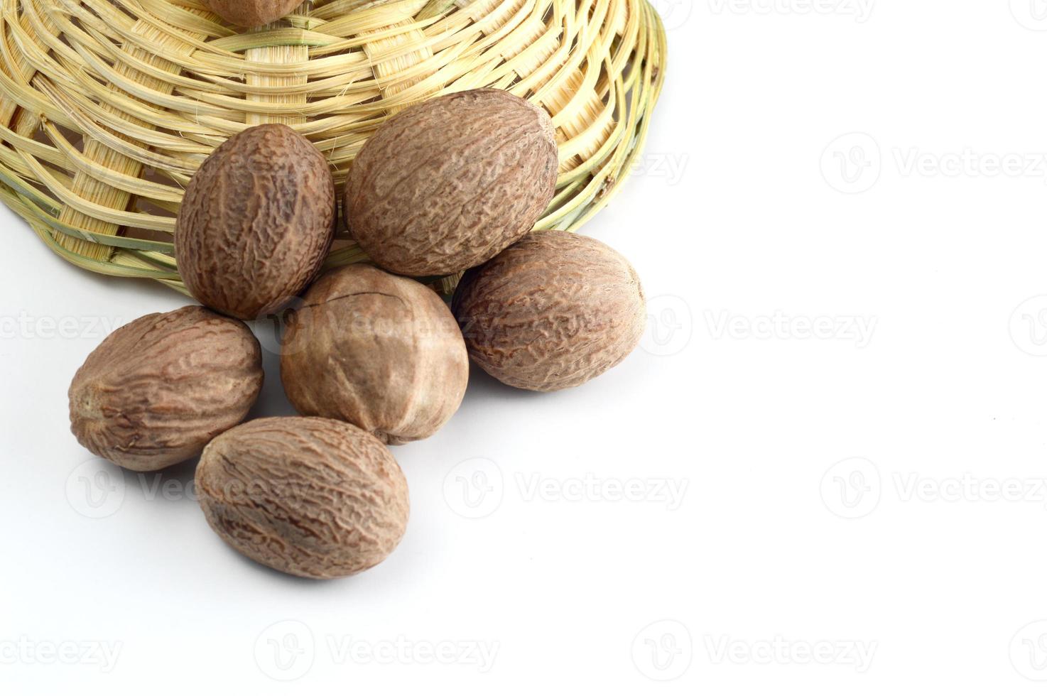 Nutmeg in bamboo basket isolated on white background photo