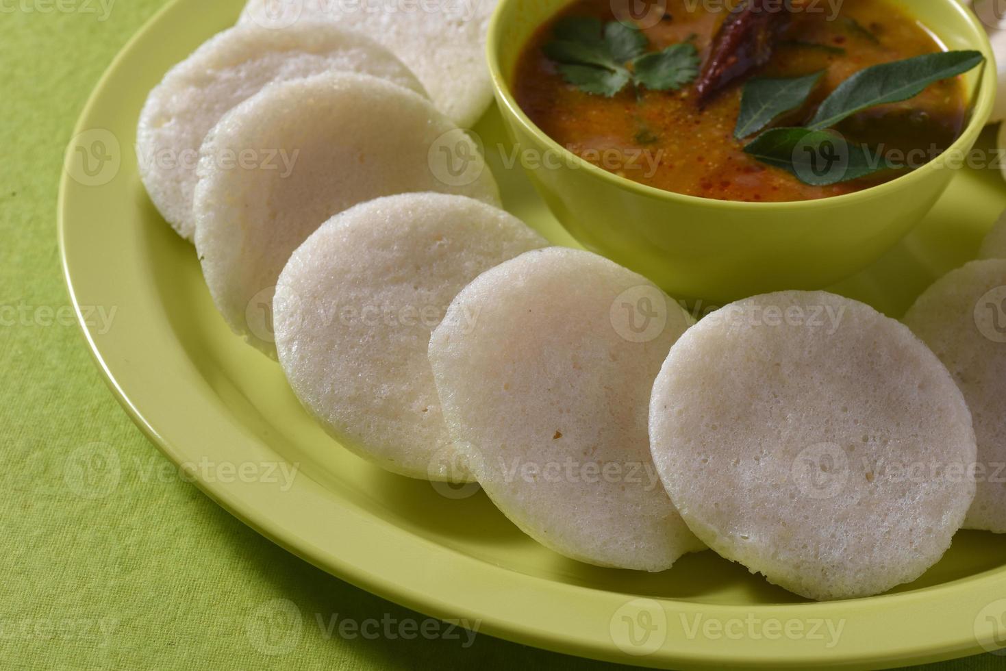 Idli with Sambar in bowl on green background, Indian Dish south Indian favourite food rava idli or semolina idly or rava idly, served with sambar and green coconut chutney. photo