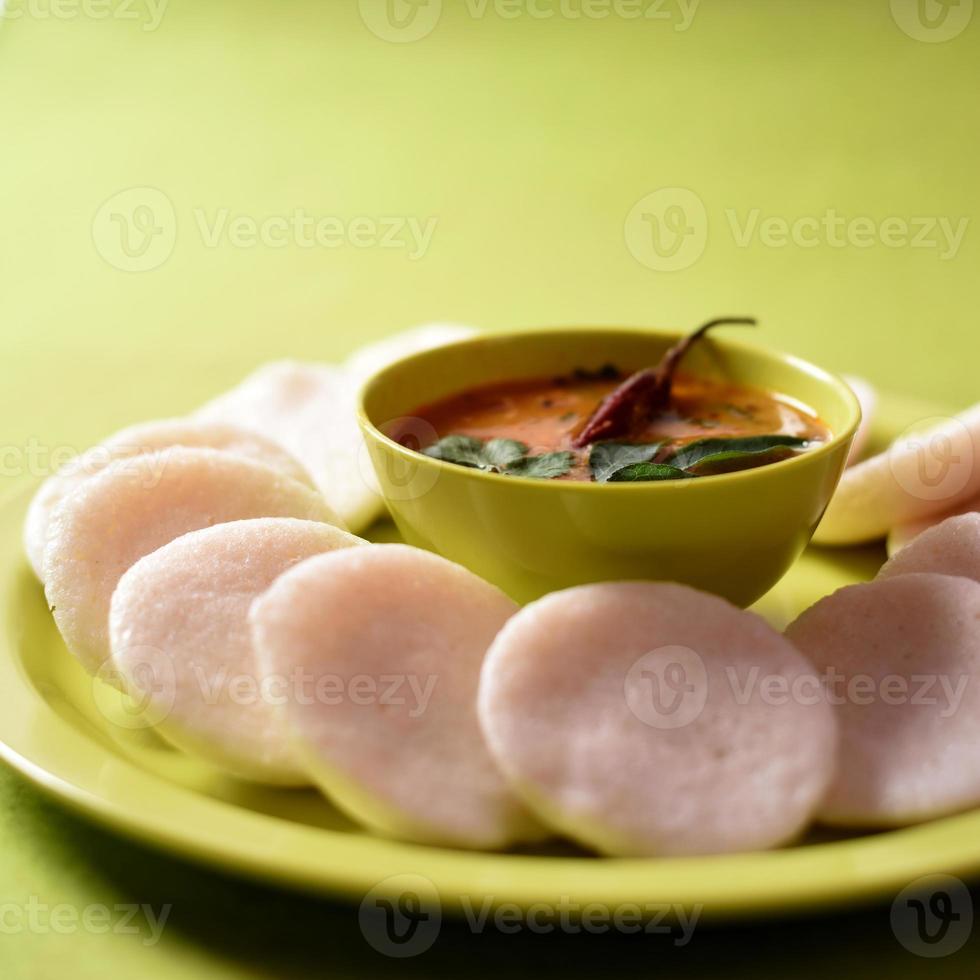 Idli with Sambar in bowl on green background, Indian Dish south Indian favourite food rava idli or semolina idly or rava idly, served with sambar and green coconut chutney. photo