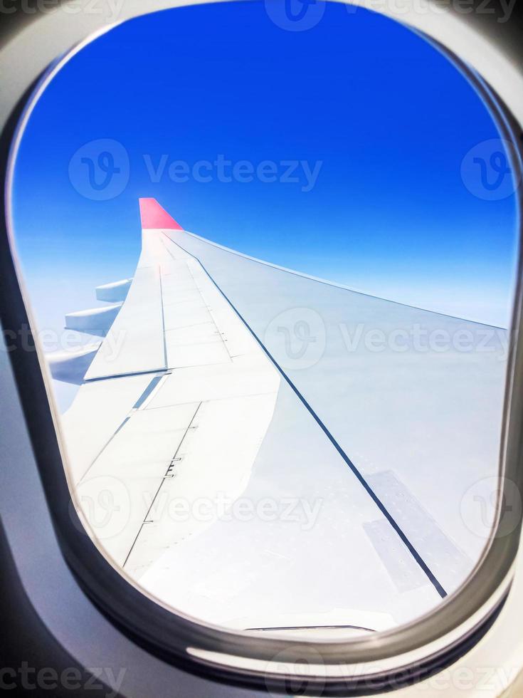 View of a commercial airplane from the window where you can see the wing which flies above the clouds at a height of 35,000 feet. photo