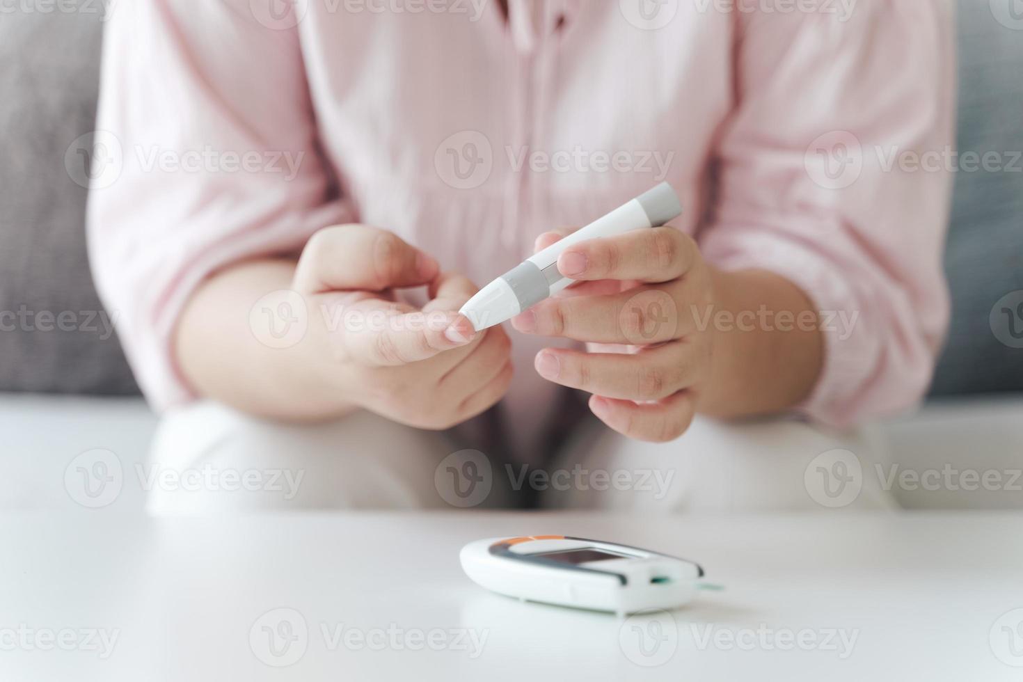 Asian woman using lancet on finger for checking blood sugar level by Glucose meter, Healthcare and Medical, diabetes, glycemia concept photo