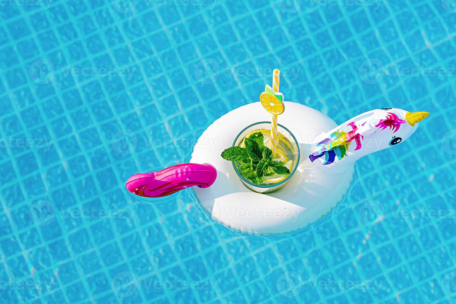 Fresh coctail mojito on inflatable white unicorn toy at swimming pool. Vacation concept. photo