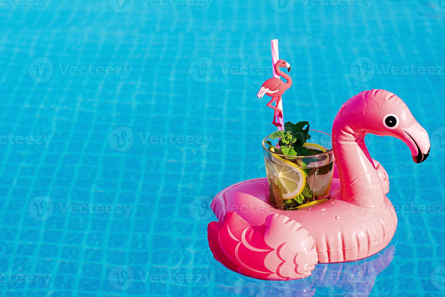 mojito de cóctel fresco en un juguete inflable de flamenco rosa en la piscina. concepto de vacaciones. foto