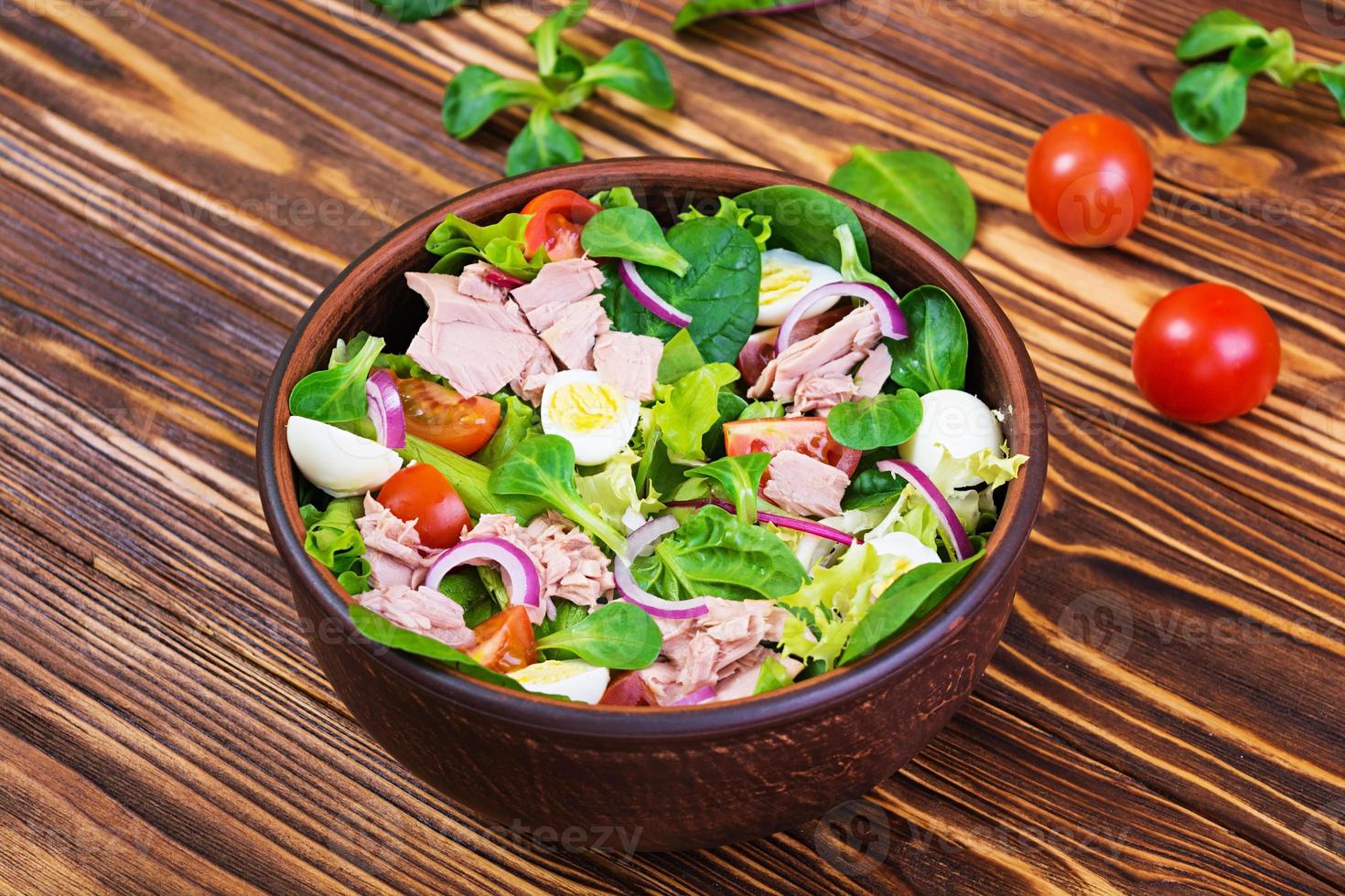 Salad with tuna, tomatoes, quail eggs, asparagus and onions on wooden background photo
