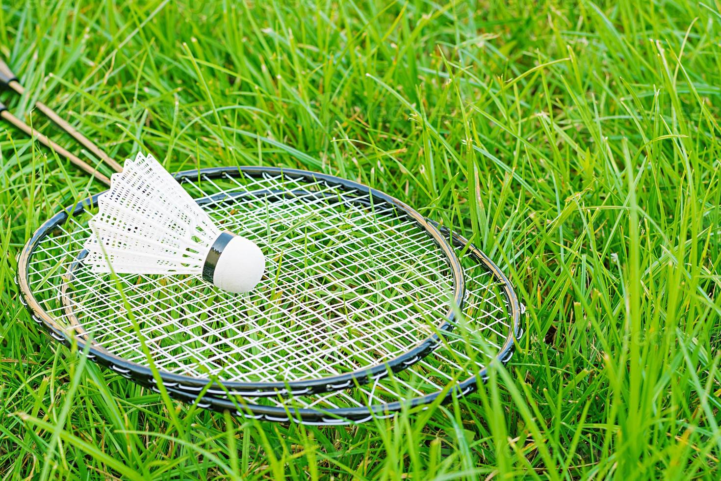 Shuttlecock and badminton rackets on a green lawn photo