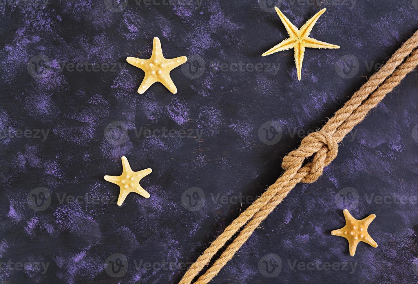 Rope and starfish on dark background. Top view photo