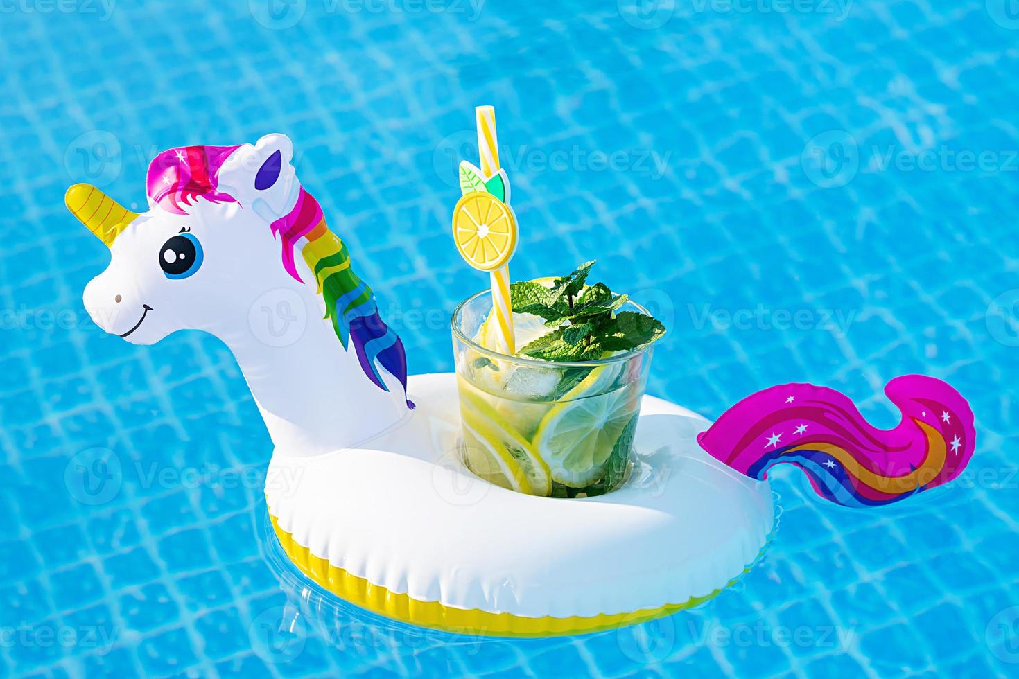 Fresh coctail mojito on inflatable white unicorn toy at swimming pool. Vacation concept. photo