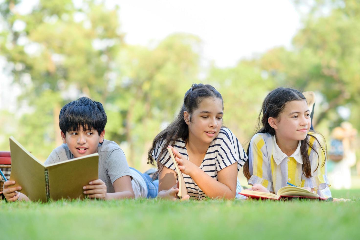 un niño indio mitad tailandés y una amiga mitad europea tailandesa aprendiendo fuera de la escuela en el parque foto