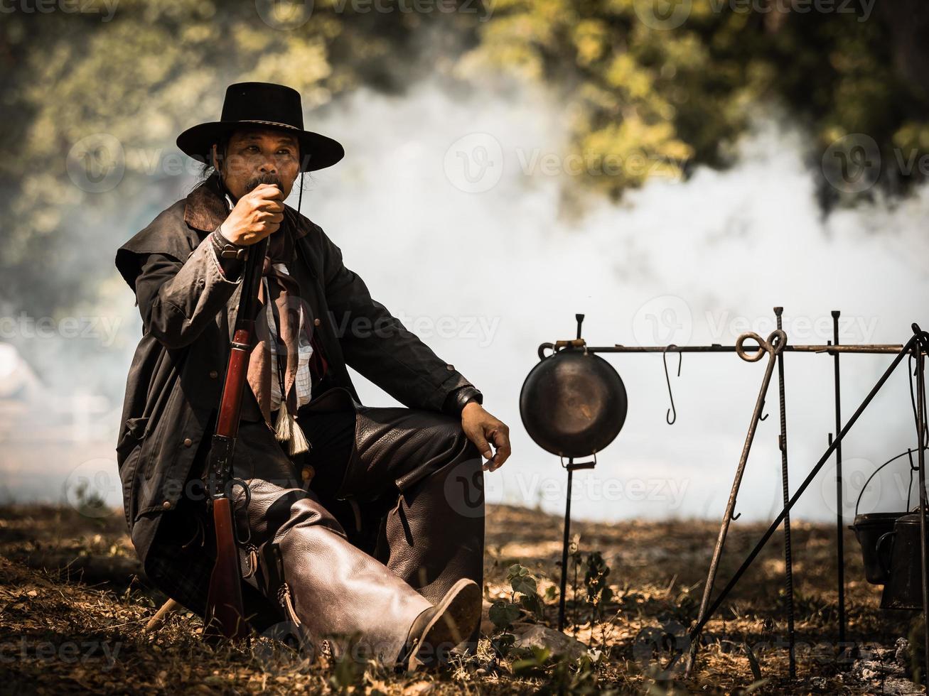 A senior cowboy sat with a gun to guard the safety of the camp in the western area photo