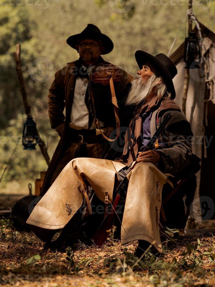 Two senior cowboys are drinking water while protecting the safety of the camp in the western area photo