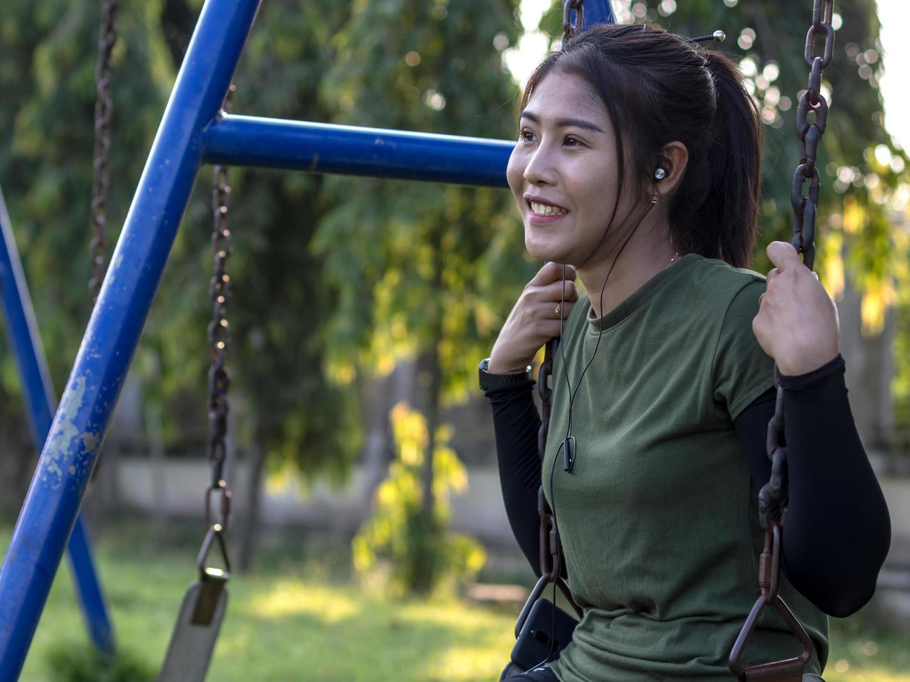 adolescente sentada en una cadena de columpio sonriendo. foto