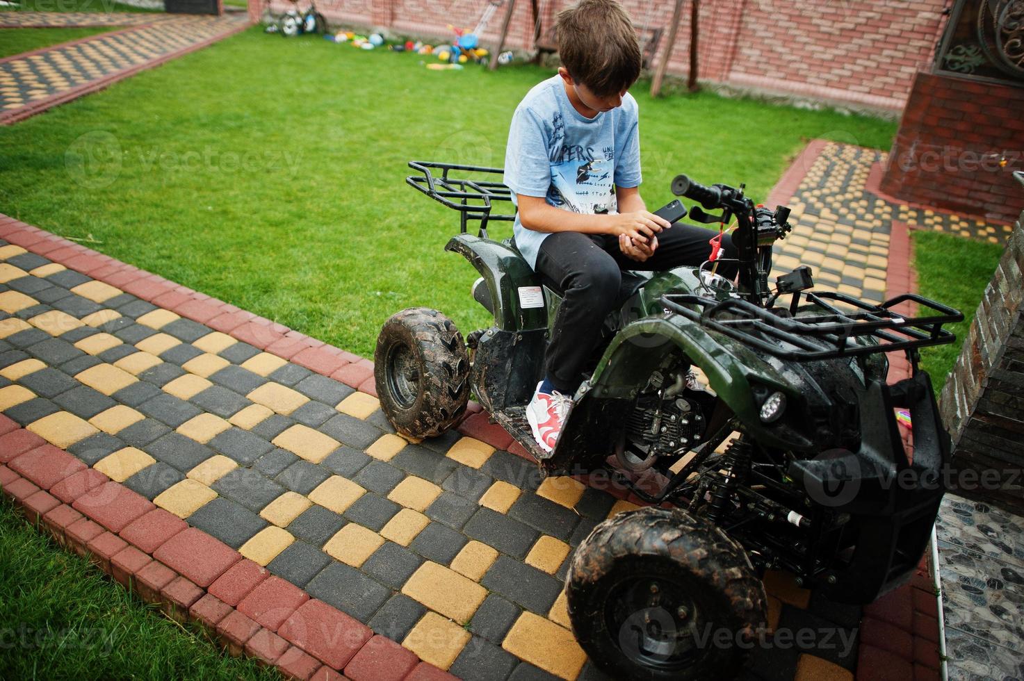 Boy in four-wheller ATV quad bike with mobile phone. photo
