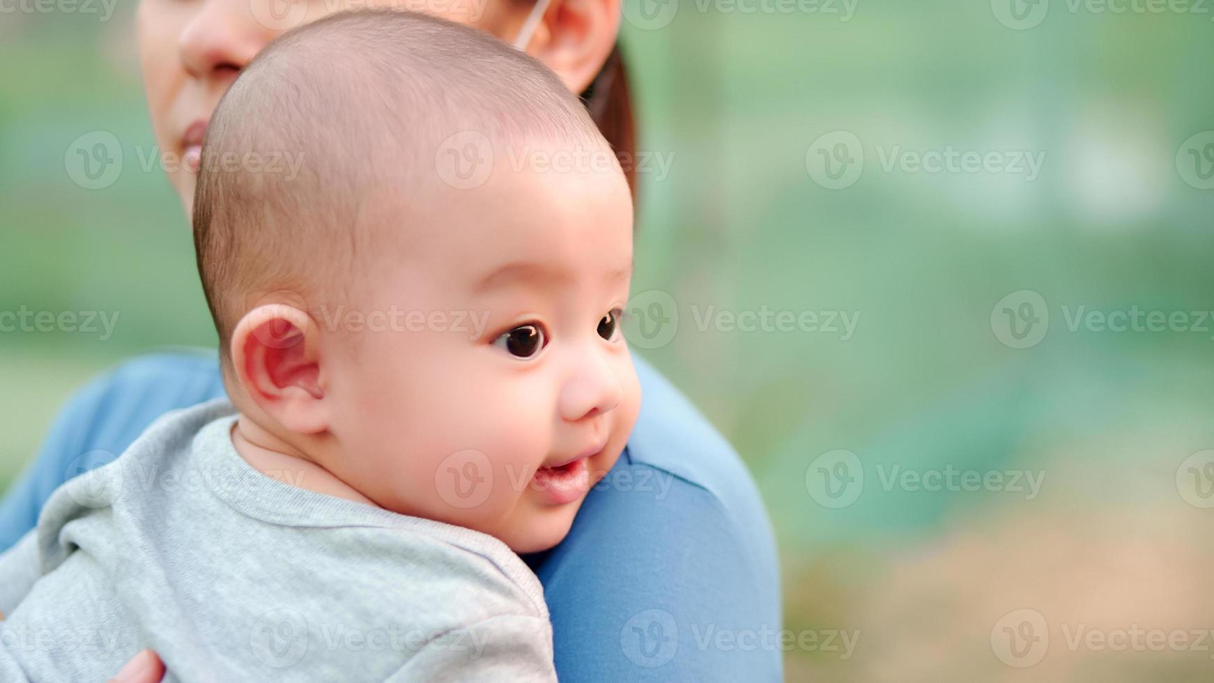 Cute, newborn Asian baby with smiling happy face. Family happy, Asian young mother is carrying and taking care with love. Little innocent new infant child in first day of life. Mother day concept. photo