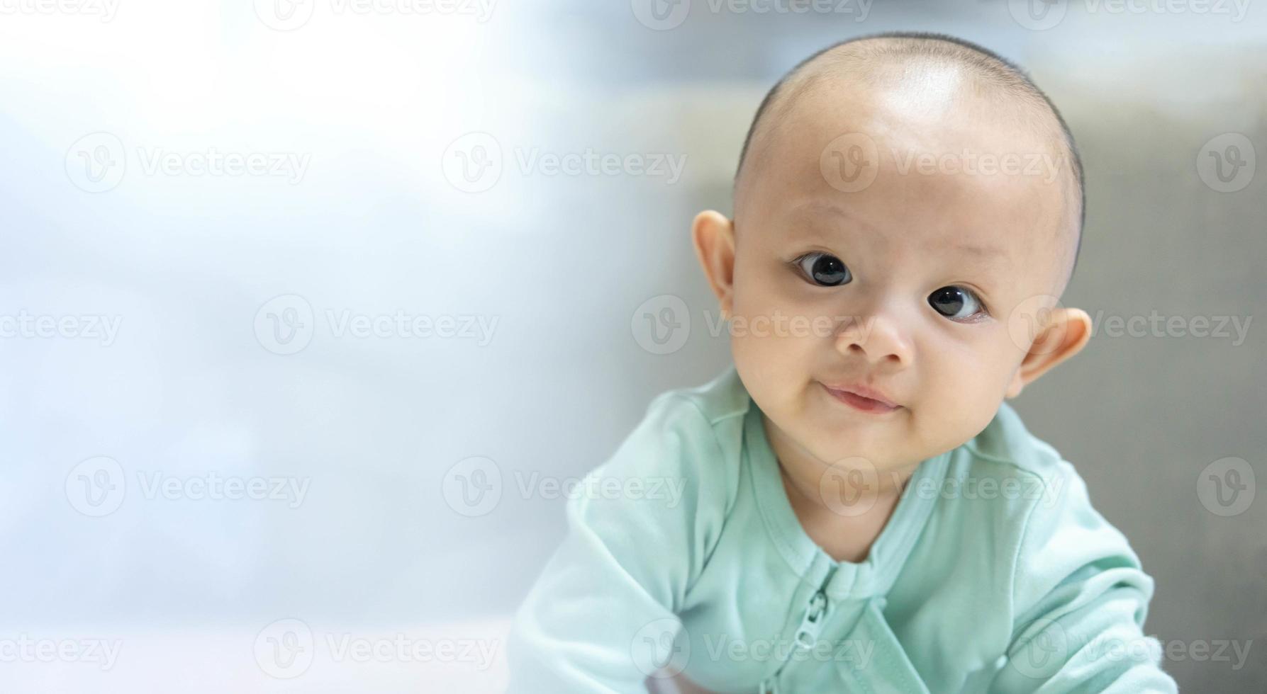 Porttrait of Adorable, Asian newborn baby looking at camera and smile happy face. Little innocent new infant child in first day of life. Mother day concept. photo